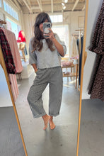 Load image into Gallery viewer, Person taking a mirror selfie wearing a gray top and checkered pants in a clothing store.
