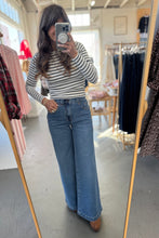 Load image into Gallery viewer, Woman taking a mirror selfie wearing a striped shirt and blue jeans in a clothing store.