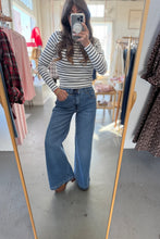Load image into Gallery viewer, Person taking a mirror selfie wearing a striped shirt and blue jeans in a clothing store.