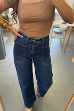 Load image into Gallery viewer, Person wearing a brown top and blue jeans indoors.