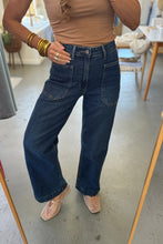 Load image into Gallery viewer, Person wearing a beige top and blue jeans indoors.
