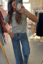 Load image into Gallery viewer, Person taking a mirror selfie wearing a light gray t-shirt and blue jeans in a clothing store.