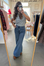 Load image into Gallery viewer, Person taking a mirror selfie wearing a light gray top and blue jeans in a clothing store.