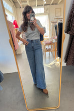 Load image into Gallery viewer, Person wearing a gray t-shirt and blue jeans standing in front of a mirror.