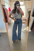 Load image into Gallery viewer, Person wearing a light gray t-shirt and blue jeans standing in front of a mirror.