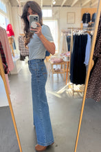 Load image into Gallery viewer, Person taking a mirror selfie wearing a light gray t-shirt and blue jeans in a clothing store.