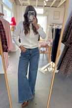 Load image into Gallery viewer, Person taking a mirror selfie wearing a white sweater and blue jeans in a clothing store.