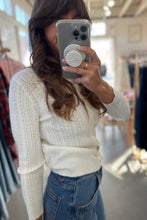 Load image into Gallery viewer, Person wearing a white sweater and blue jeans taking a mirror selfie in a store.