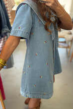 Load image into Gallery viewer, Person wearing a denim dress with floral embroidery in an indoor setting