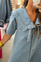 Load image into Gallery viewer, Woman wearing a denim dress with floral embroidery in a store setting