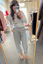 Load image into Gallery viewer, Woman taking a mirror selfie wearing a striped top and checkered pants in a clothing store.