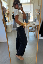 Load image into Gallery viewer, Person taking a mirror selfie wearing a white t-shirt and black pants in a room with a large mirror.