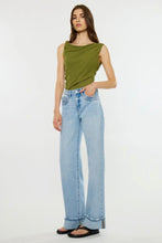 Load image into Gallery viewer, A model wearing a sleeveless olive green top and light-wash wide-leg blue jeans, standing against a plain white studio background.