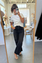 Load image into Gallery viewer, Person taking a mirror selfie wearing a white t-shirt and black pants in a store.