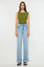 Load image into Gallery viewer, A model stands against a plain white studio background wearing a sleeveless olive green top with a wide draped neckline, light-wash wide-leg blue jeans, and black sandals.