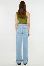 Load image into Gallery viewer, A woman viewed from behind wearing light-wash wide-leg jeans with rolled cuffs, a green sleeveless top, and black shoes against a plain white studio background.