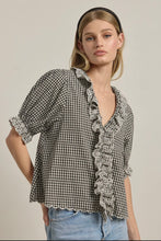 Load image into Gallery viewer, Woman wearing a black and white checkered blouse with ruffled details on a plain background