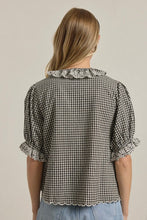 Load image into Gallery viewer, Woman wearing a black and white checkered blouse with lace details on a beige background