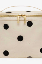 Load image into Gallery viewer, An off-white canvas cosmetic bag with black polka dots and a gold zipper closure, shown against a plain white background.