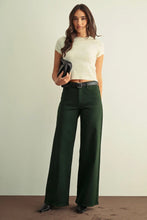 Load image into Gallery viewer, A woman modeling a cream short-sleeve knit crop top and dark forest green wide-leg trousers with a black belt, holding a black clutch against a neutral studio background.