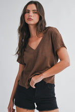 Load image into Gallery viewer, A woman wearing a brown short-sleeve V-neck top and black denim shorts, photographed against a plain light gray studio background.