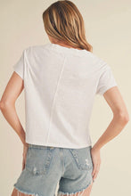 Load image into Gallery viewer, A woman shown from the back wearing a white short-sleeve crop top and light-wash denim shorts against a plain beige studio background.