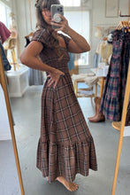 Load image into Gallery viewer, Person wearing a brown plaid dress taking a mirror selfie in a clothing store.
