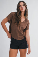 Load image into Gallery viewer, A woman modeling a brown short-sleeve V-neck top with black denim shorts against a light gray studio background.