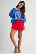 Load image into Gallery viewer, Woman wearing a blue sweater with fish design and red shorts on a white background