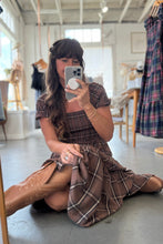 Load image into Gallery viewer, Woman taking a mirror selfie wearing a plaid dress and brown boots in a store.