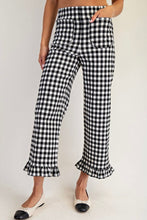 Load image into Gallery viewer, Black and white gingham cropped pants with a ruffled hem, modeled with black and white pointed flats against a plain white background.