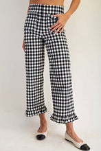 Load image into Gallery viewer, Black and white gingham cropped wide-leg pants with ruffled hems, shown on a model wearing black and white pointed flats against a light gray studio background.