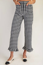 Load image into Gallery viewer, Black and white gingham cropped pants with a ruffled hem, shown on a model wearing black and white pointed flats against a light gray background.