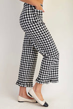 Load image into Gallery viewer, Black and white gingham cropped pants with a ruffled hem, shown on a model wearing white pointed flats against a light gray studio background.