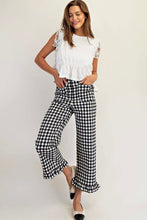 Load image into Gallery viewer, A woman modeling a white ruffled sleeveless top and black-and-white gingham wide-leg cropped pants with ruffled hems, standing against a light gray studio background.