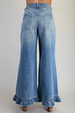 Load image into Gallery viewer, Back view of a person wearing light blue wide-leg denim jeans with ruffled hems, shown against a plain light gray studio background.