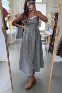 Person wearing a striped dress standing in front of a mirror in a room with furniture.