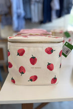 Load image into Gallery viewer, A cream-colored canvas zippered lunch bag with a red strawberry pattern, featuring the 'JUST DESERTS' brand name and a green product tag, displayed on a white table in a store setting.
