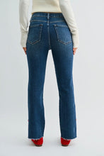 Load image into Gallery viewer, Rear view of a person wearing dark blue denim jeans with a straight-to-medium leg, frayed hems, and red shoes, paired with a cream ribbed sweater, against a light gray studio background.
