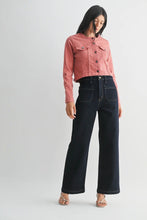Load image into Gallery viewer, A model wearing a dusty rose cropped denim jacket and dark navy wide-leg jeans, standing against a light gray studio background.