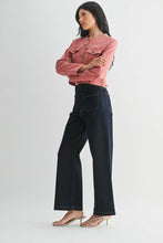 Load image into Gallery viewer, A woman modeling a dusty pink cropped denim jacket and dark wide-leg jeans against a light gray studio background.