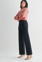 Load image into Gallery viewer, Woman wearing a pink blouse and dark blue jeans on a white background