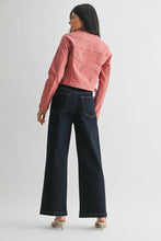 Load image into Gallery viewer, A woman shown from the back wearing a cropped dusty pink denim jacket, dark wide-leg denim jeans, and beige high-heeled sandals against a light gray studio background.
