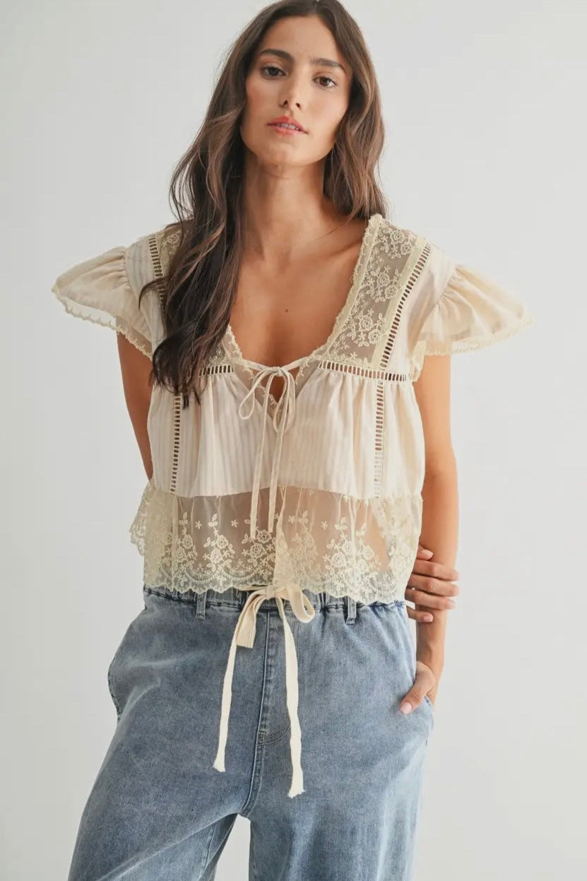 Woman wearing a lace top and jeans on a plain background