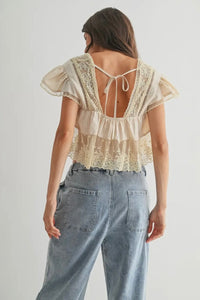 Woman wearing a lace top and jeans on a plain background