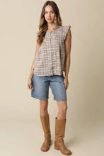 Load image into Gallery viewer, A woman modeling a sleeveless plaid button-up top in beige and brown tones, paired with denim shorts and tan knee-high boots, against a plain beige studio background.