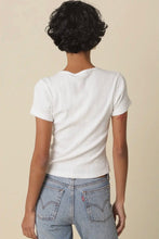 Load image into Gallery viewer, A person shown from the back wearing a white short-sleeve ribbed knit top and light blue jeans against a plain beige studio background.
