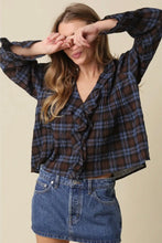 Load image into Gallery viewer, A woman wearing a dark brown and blue plaid long-sleeve blouse with a ruffled front, paired with a blue denim mini skirt, posing against a solid beige background.