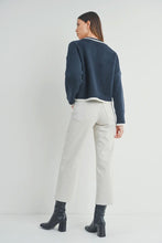 Load image into Gallery viewer, Woman wearing a navy sweater and white pants on a plain background