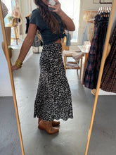 Load image into Gallery viewer, Person wearing a black floral skirt in a clothing store.